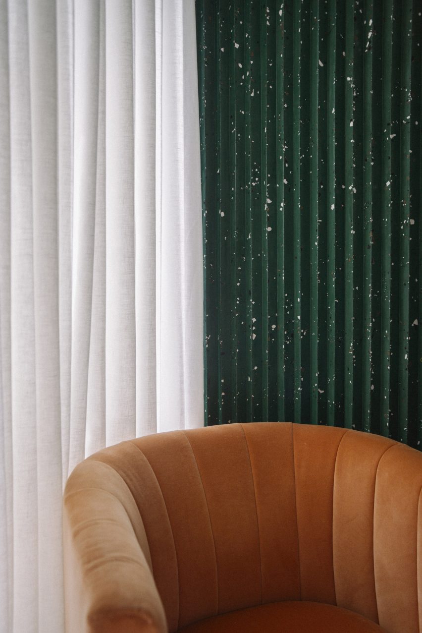 An orange chair against green terrazzo walls