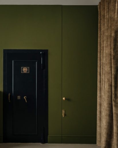 Vault door in olive green-painted guest studio of Unearthed Vault apartment