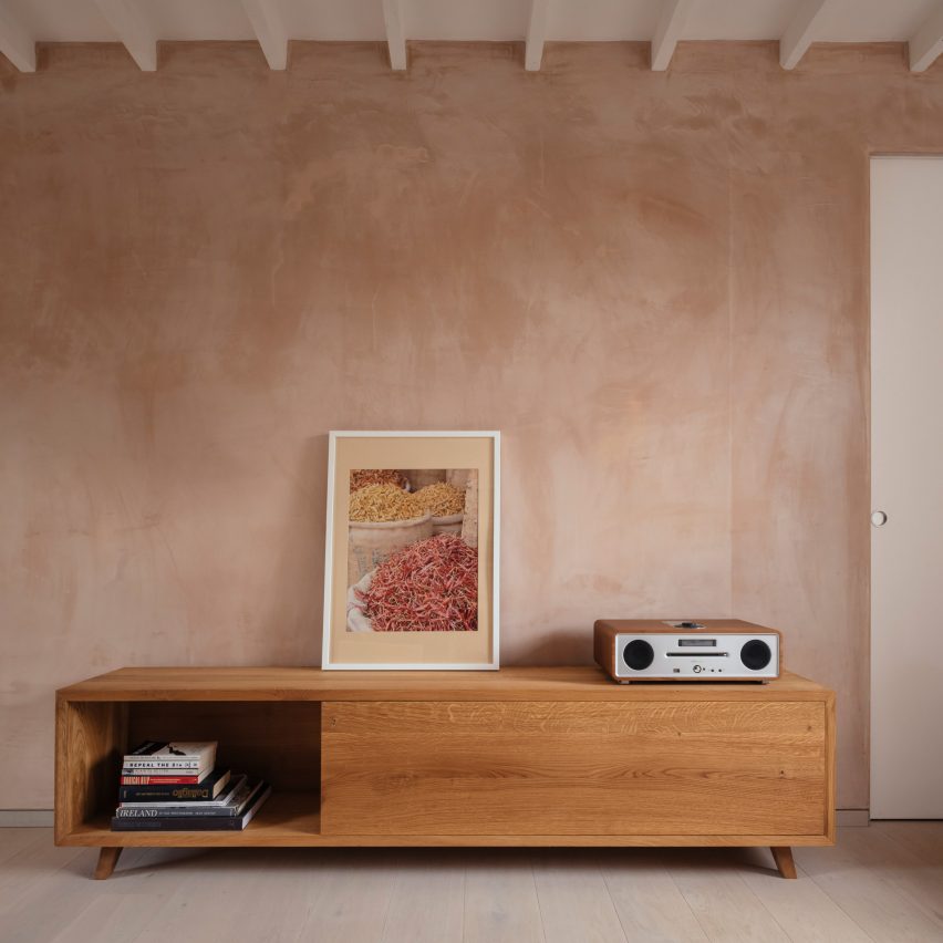 Timber console with art objects against a blush pink wall