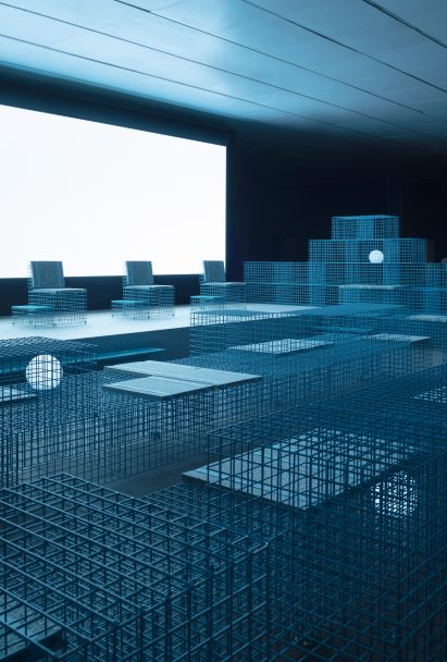 A row of mesh chairs sits on a stage by Clap Studio