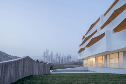 An undulating fence surrounds the hotel
