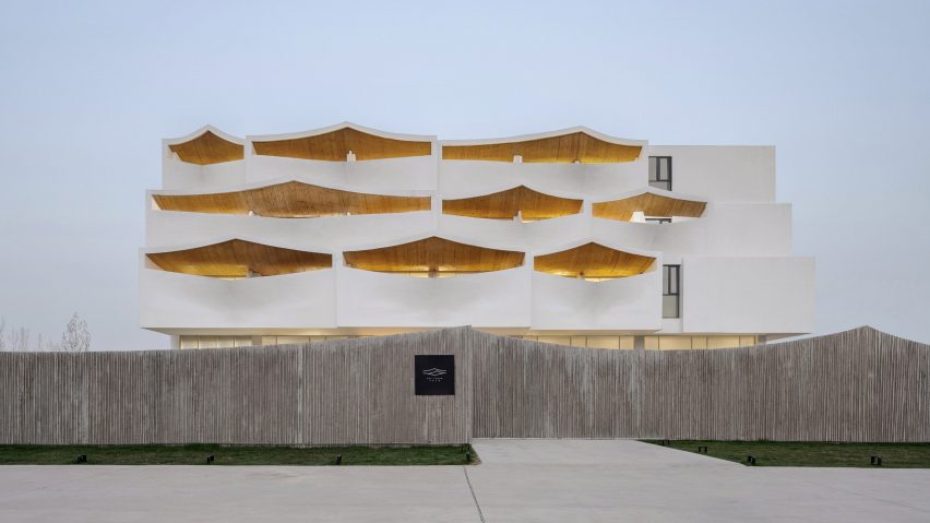 A wooden fence surrounds the hotel