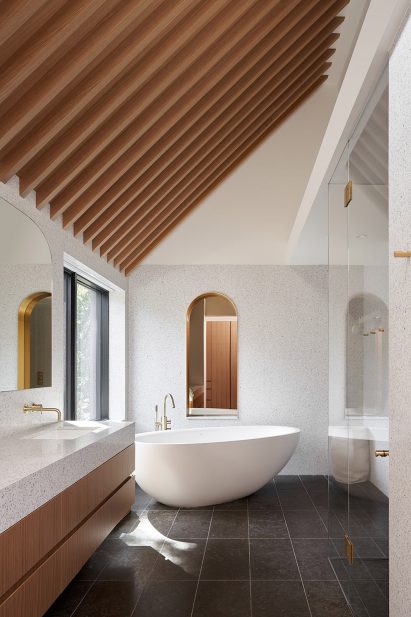 The bathroom has pink-hued marble and a curved bathtub