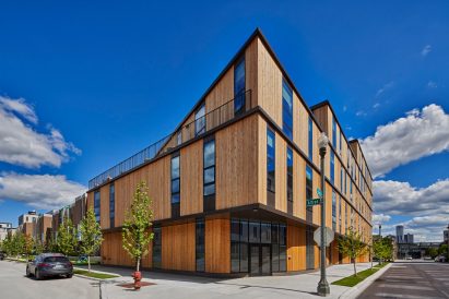 The apartment building is clad in reddish cedar