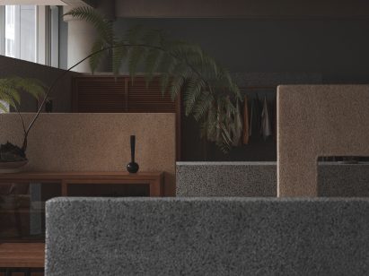 Washed stone partition walls in grey and beige in store interior by BLUE Architecture Studio
