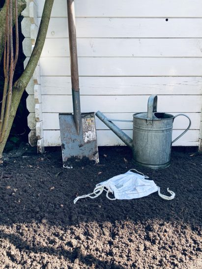 Two Marie Bee Bloom masks in soil in a garden