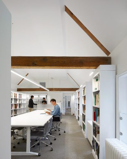 A white-walled library with exposed wooden beams