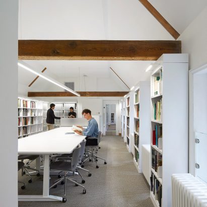 A white-walled library with exposed wooden beams