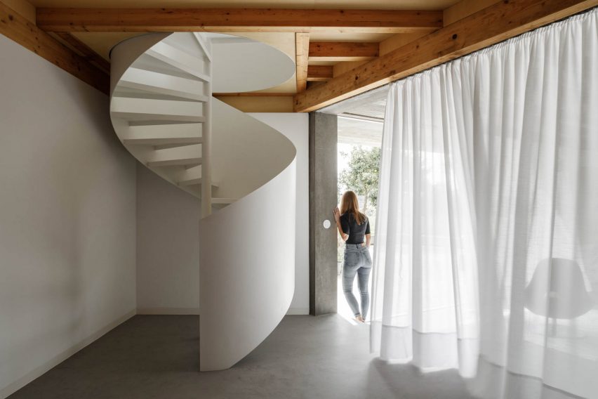 A white spiral staircase is tucked behind a curtain