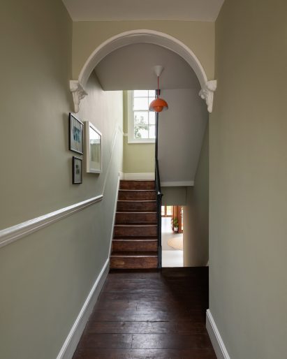 A hallway will pale green walls and hardwood floors