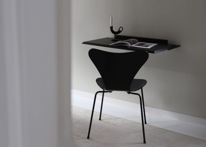 Black version of the Alada desk affixed to a wall with ornaments sat atop