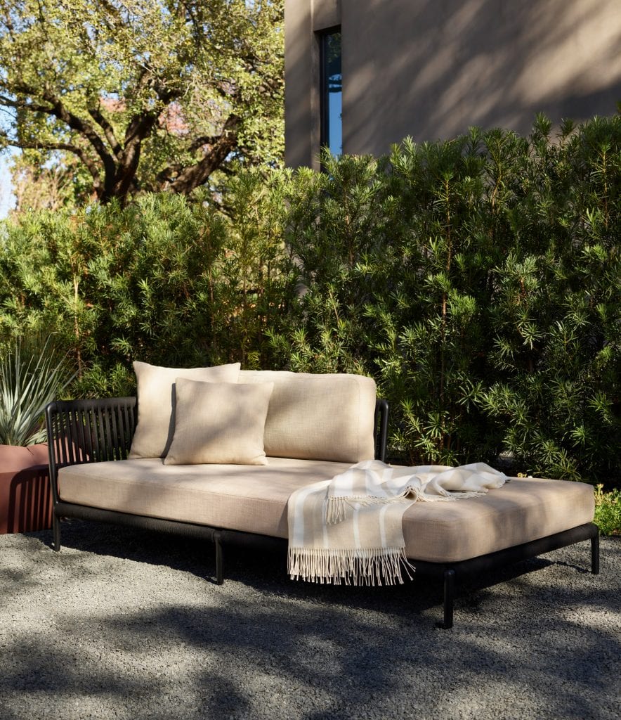 A sectional earthy-coloured sofa with an accompanying throw