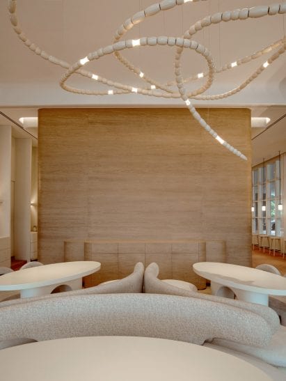 Seating area with oak veneer walls and sculptural chandelier made from wooden beads in restaurant interior by Ashiesh Shah