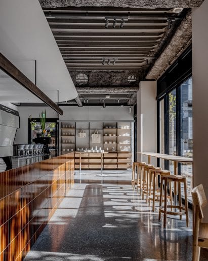 Brown-tiled bar and wooden counter seating in coffee shop by Keiji Ashizawa Design