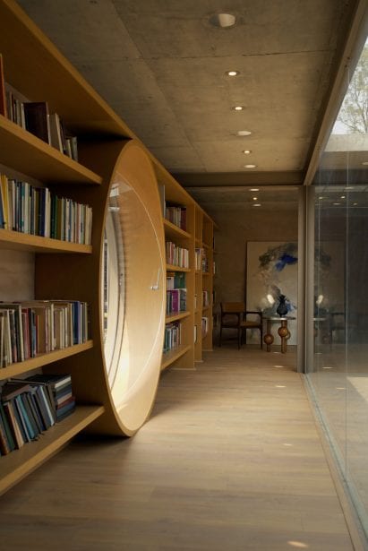 Round glass door between bookshelves in Casa UC by Daniela Bucio Sistos
