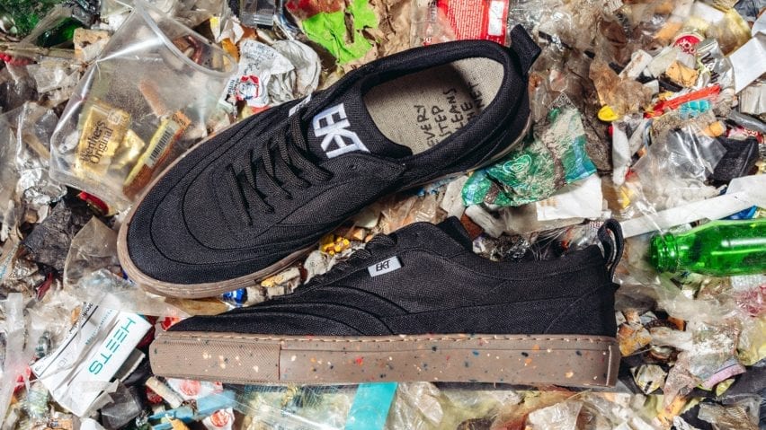 A pair of black trainers photographed on rubbish