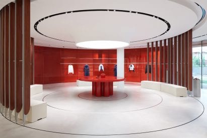 Display stand surrounded by red glass wall in store interior by Sybarite
