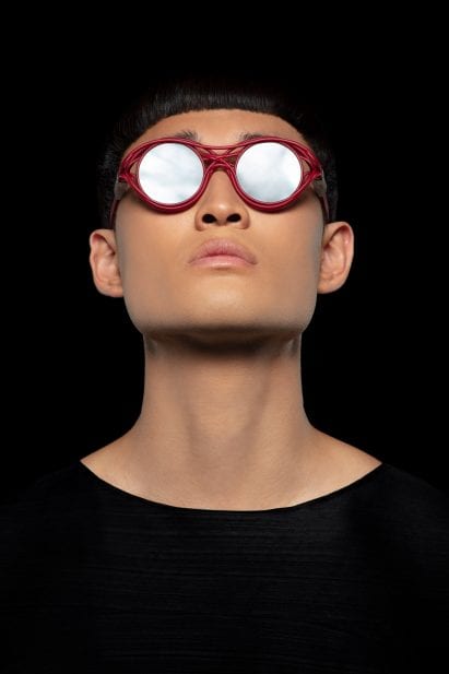 A man wearing a red pair of Kengo Kuma's sunglasses