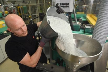Man pouring recycled plastic pellets into funnel