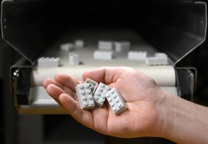 A hand holding 4 Lego bricks