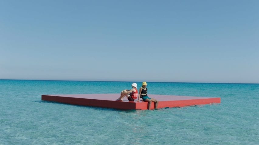 Two male models sit on a floating red plank