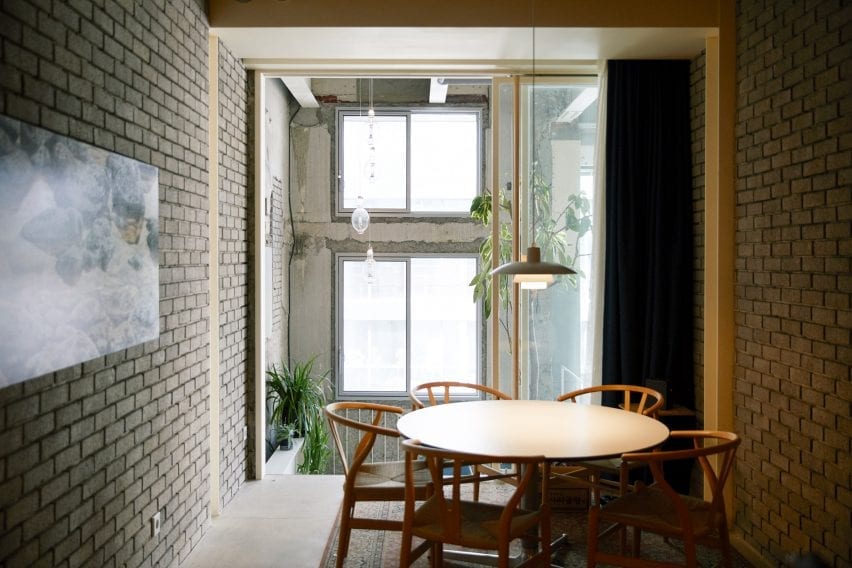 A round wooden table is pictured beside a brick wall