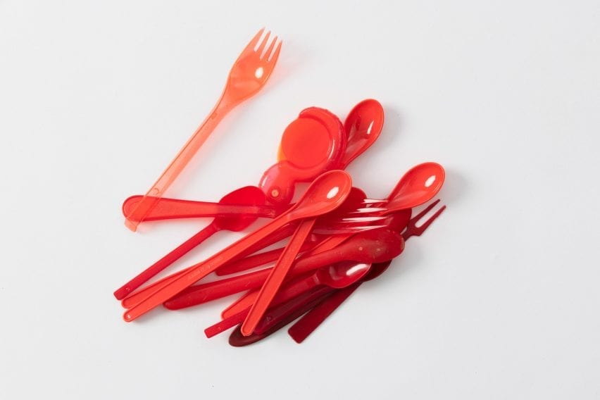Red hued cutlery is placed in a pile