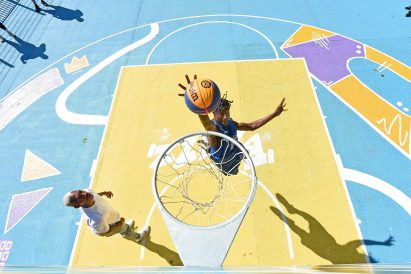 Two players play basketball on a colourful court
