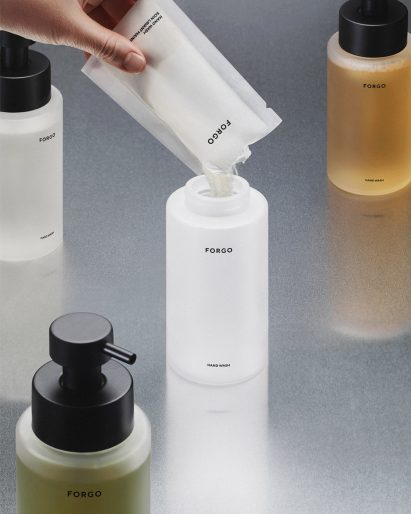 Hand refilling glass soap bottle with concentrated powder