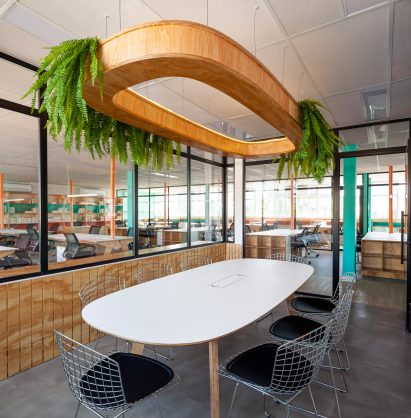 Suspended over a dining table is a wooden lighting installation that can hold potted plants