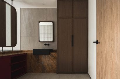 Wooden doors and red stone counters in bathroom of Buda Hotel