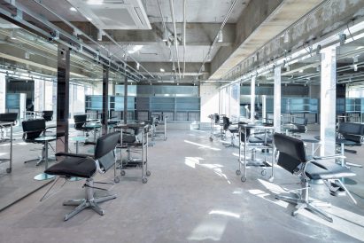 Hair dressing setups with suspended mirrors and concrete floors by Schemata Architects