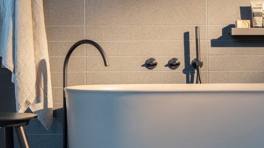 A white bath and steel sink inside a bathroom