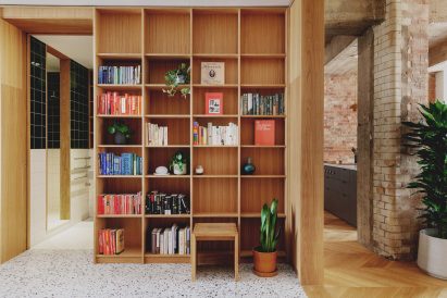 Entrance library with oak shelving in St John Street warehouse apartment by Emil Eve Architects