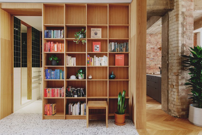 Entrance library with oak shelving in St John Street warehouse apartment by Emil Eve Architects