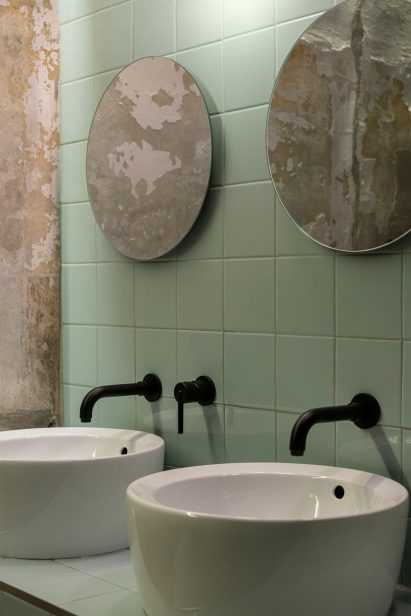 Bathroom with mint green tiles and exposed concrete