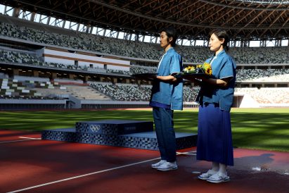 Medal beareres in front of a podium in a sports stadium