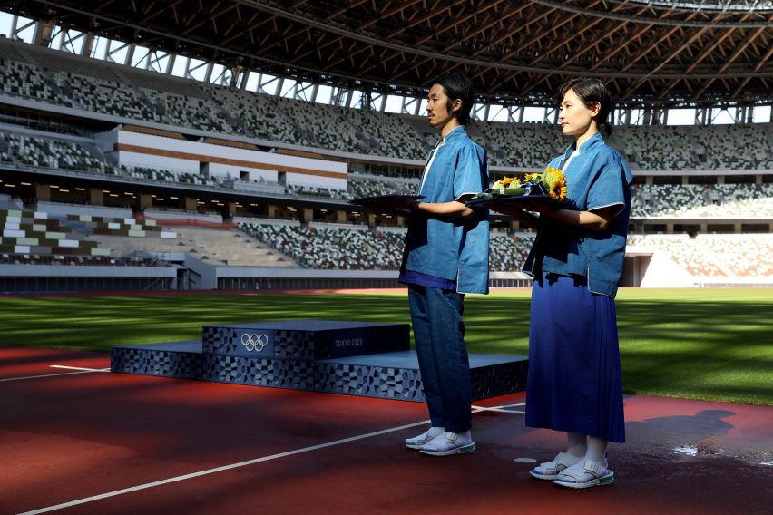 Medal beareres in front of a podium in a sports stadium
