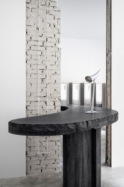 Curved concrete table with chrome light in 6:19 Studio
