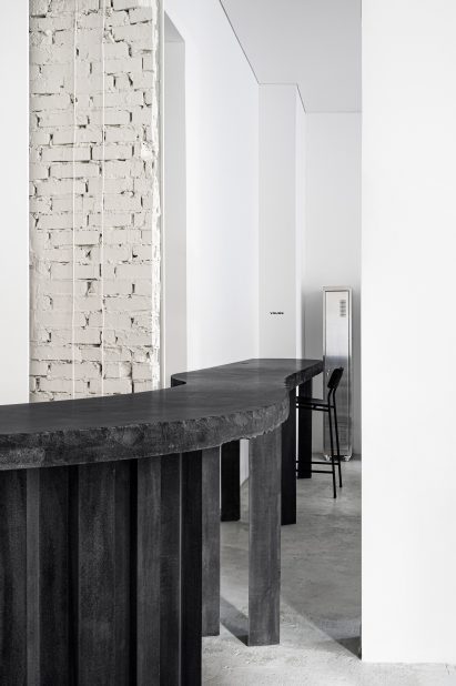 Black concrete table with high chair in tattoo parlour by Balbek Bureau
