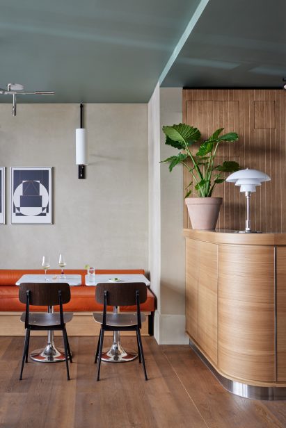 Curved wooden bar and bench seating upholsterd in orange leather in hotel interior by Fettle
