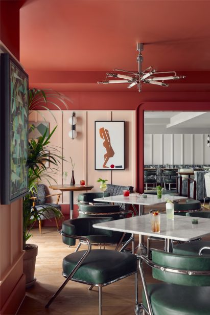 Restaurant of Schwan Locke hotel with red walls, green leather chairs and marble tables