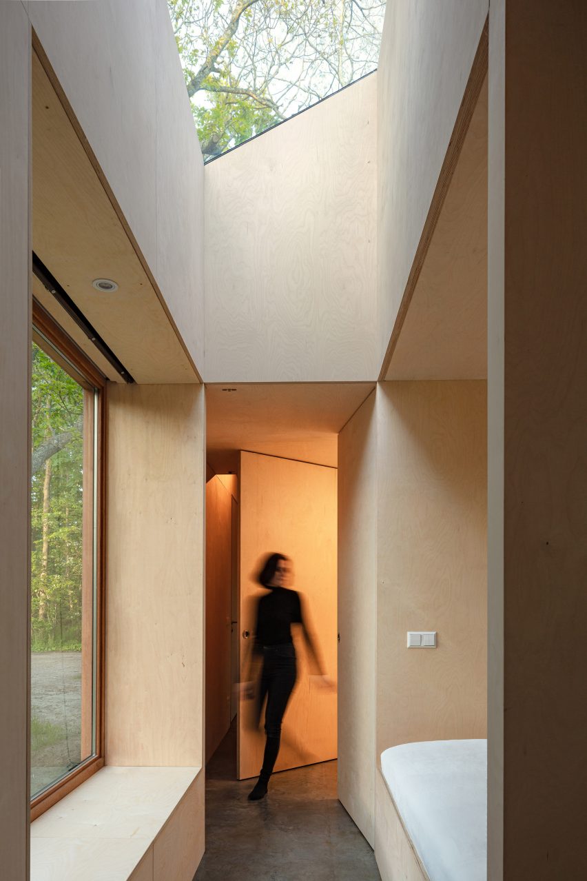 A wmoan walks through the hallway of Holiday Home by Orange Architects