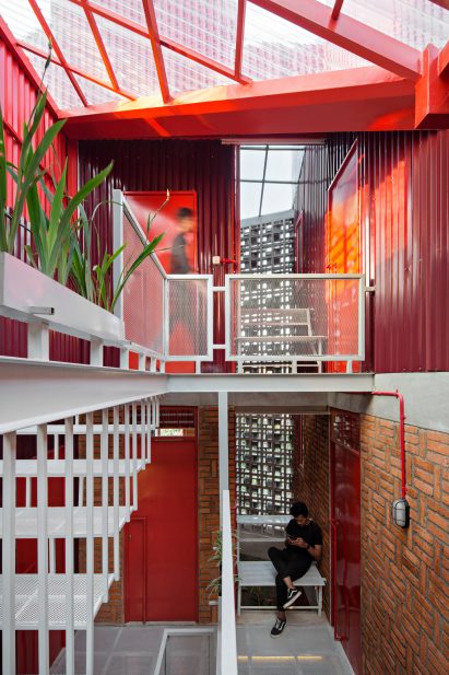 Resident sits on a bench in a nook on the white metal staircase while light comes through a transparent roof section