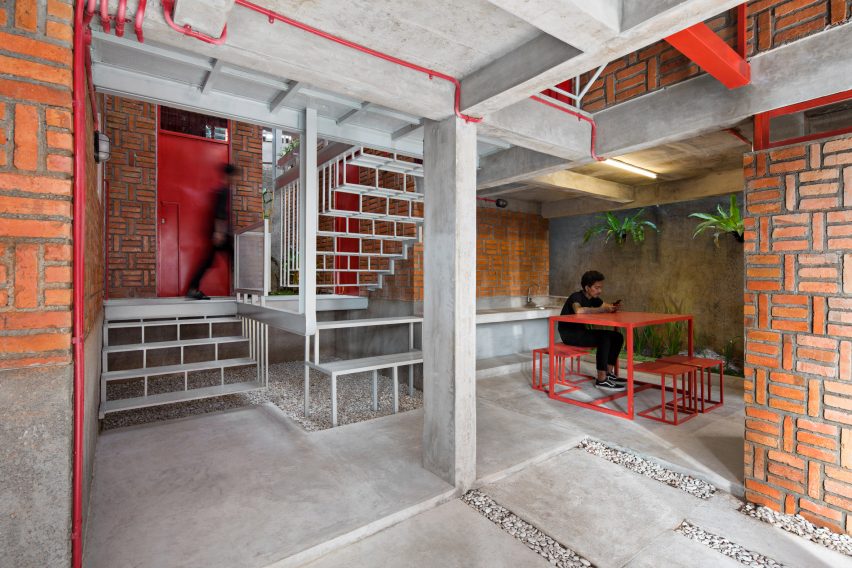 Resident sits at red table under a white metal staircase