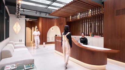 A patient walks to the wooden reception desk in Paris Dental Studios