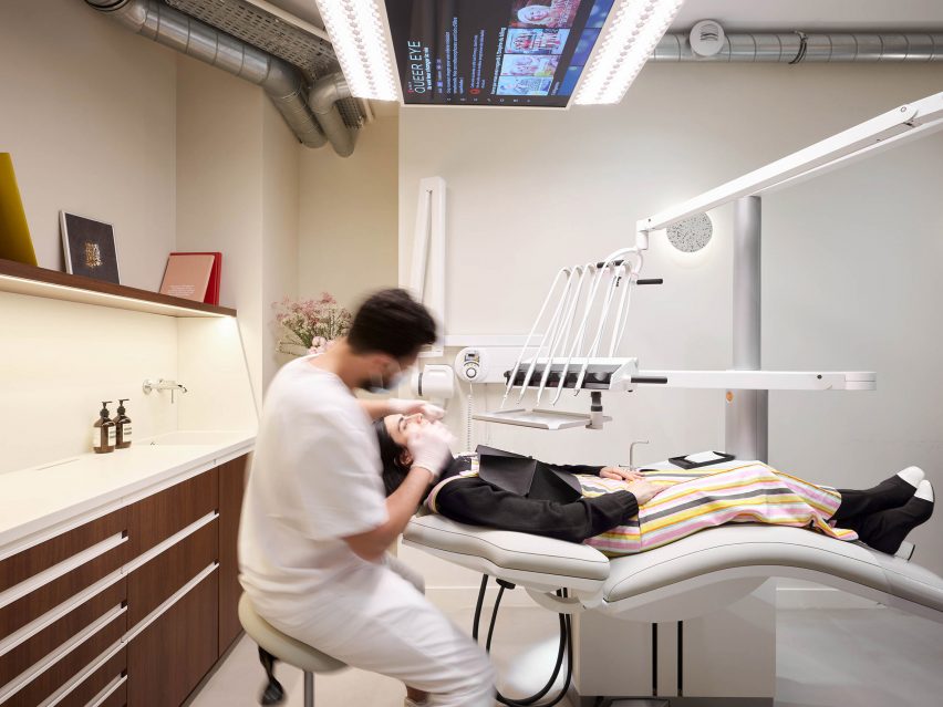 A dentist wearing white operating on a woman