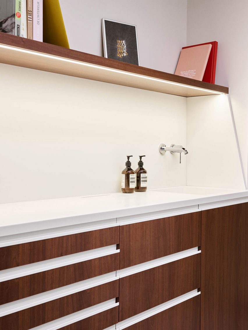 A white sink with wooden cupboards