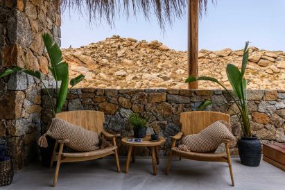 Wooden armchairs in front of stone wall of Mykonos Wellness Resort