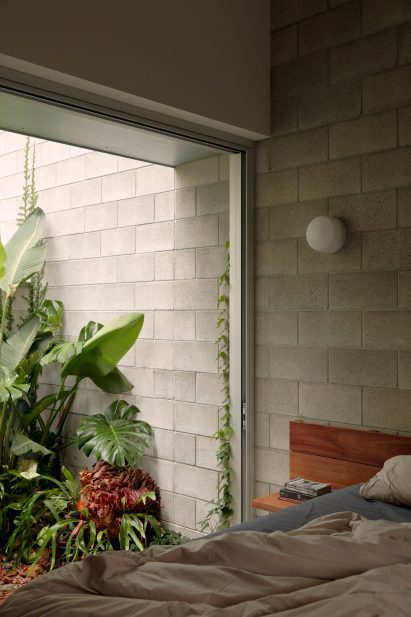Wooden bed next to floor to large window in Mt Coot-Tha House looking out at plants